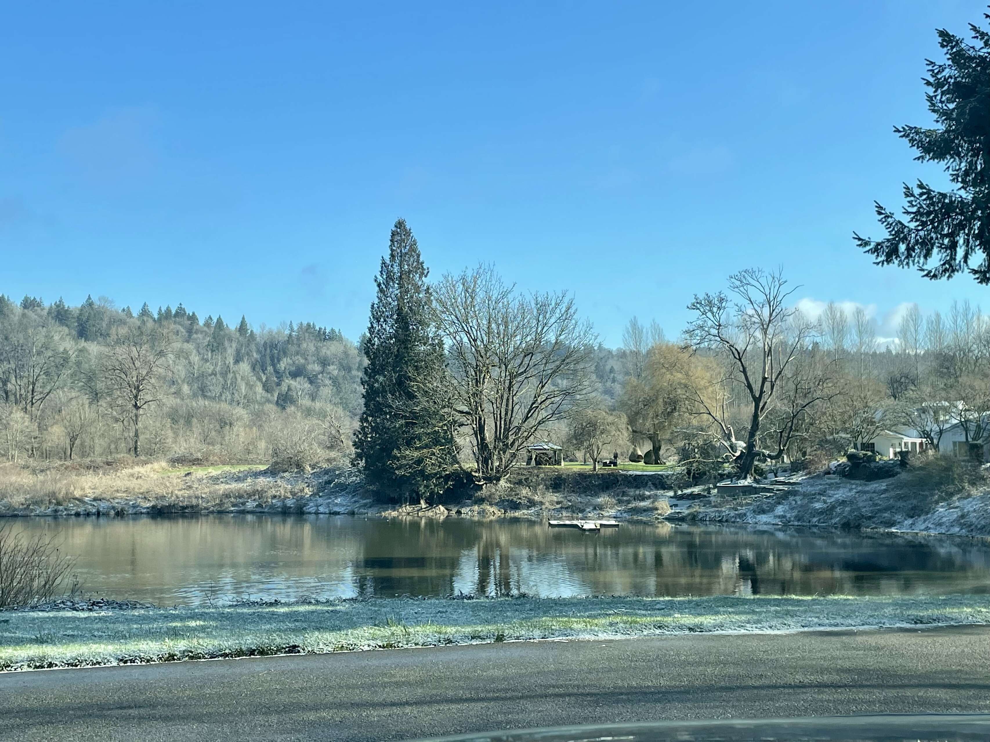 [ Photo of a slightly icy landscape featuring a pond, a tree-smattered hill, and communal areas on a large ranch in Carnation, Washington (U.S.) ]